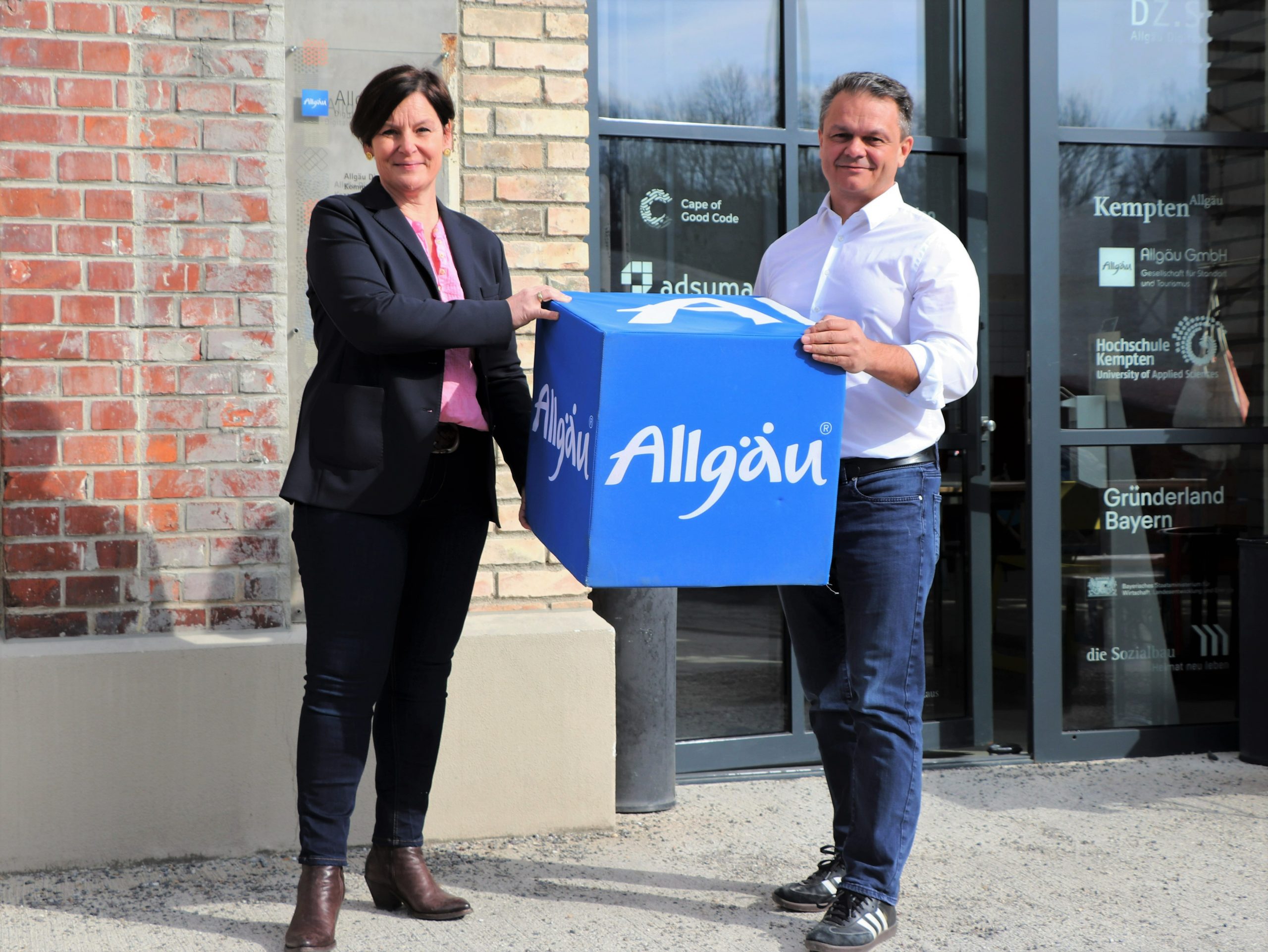 Antonia Widmer from Allgäu Digital holding a big blue Allgäu dice together with Harald Ostler the CEO of aumentoo