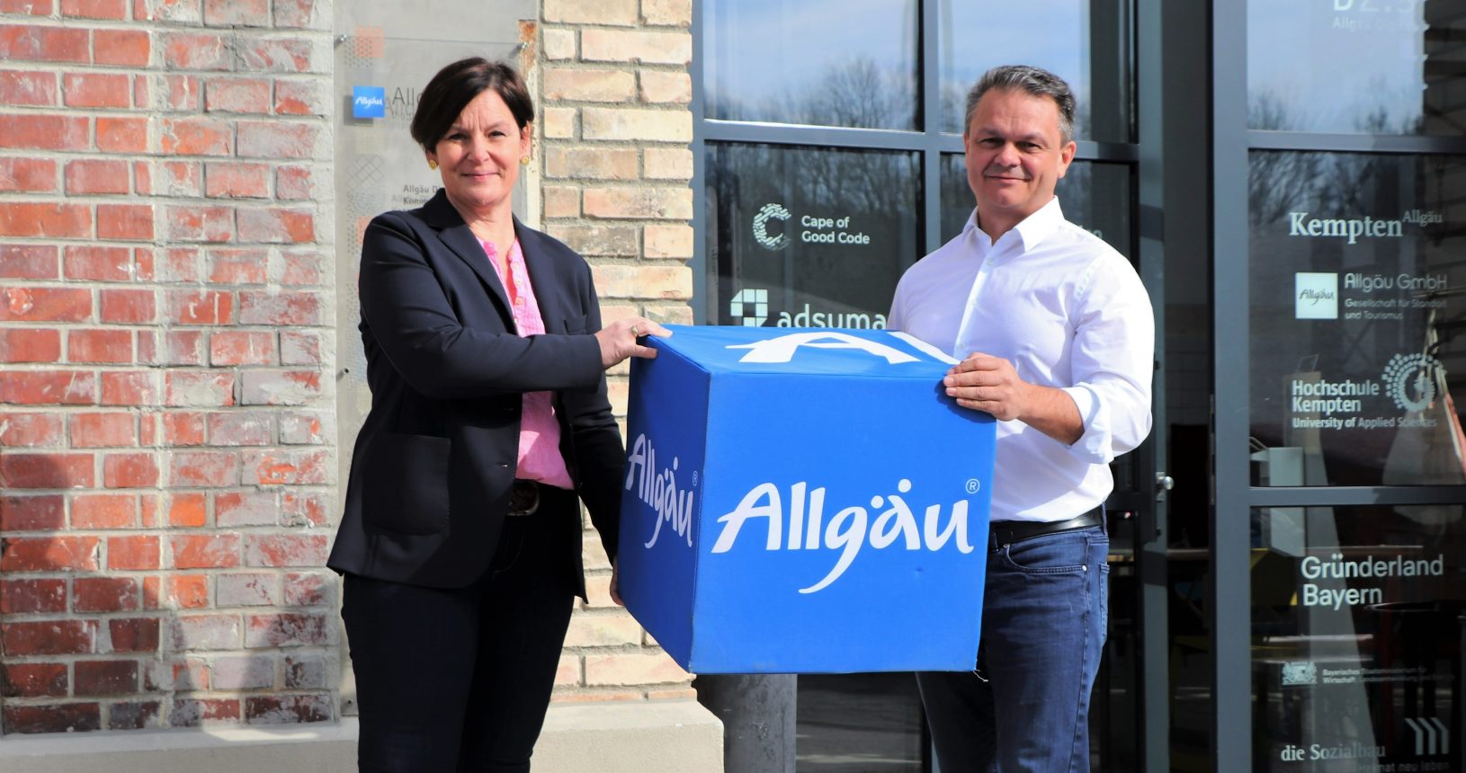 Antonia Widmer from Allgäu Digital holding a big blue Allgäu dice together with Harald Ostler the CEO of aumentoo